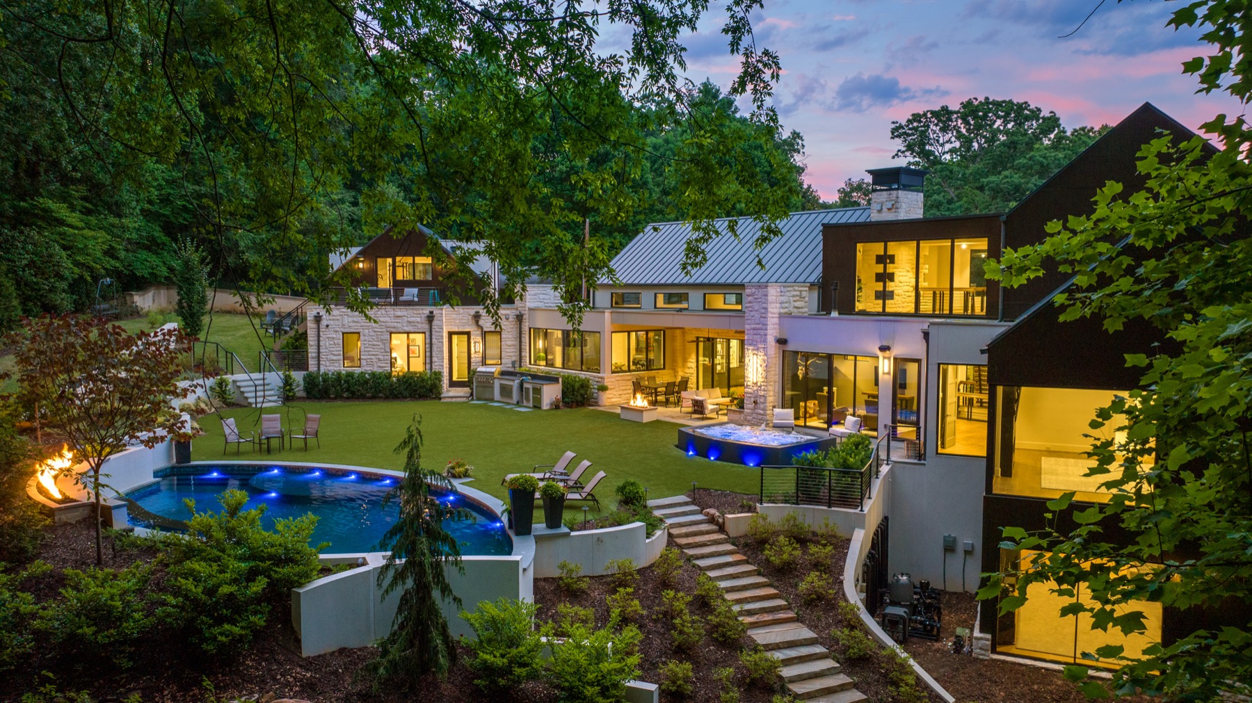 Aerial dusk view of a backyard pool, spa, and fire pit behind a modern Atlanta home