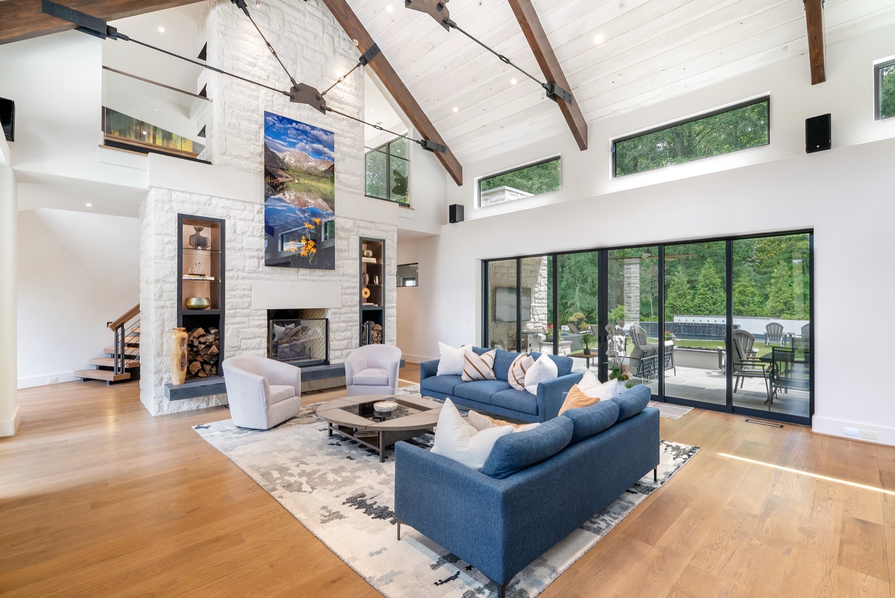 Vaulted great room with a stone fireplace and blue sofas