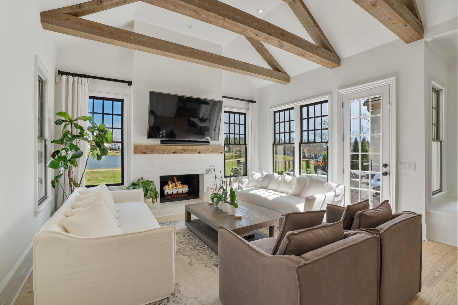 Bright living room with exposed wood beams and a lakefront view