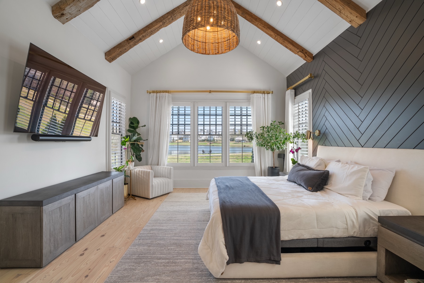 Primary bedroom with vaulted ceiling, herringbone accent wall, and lake view