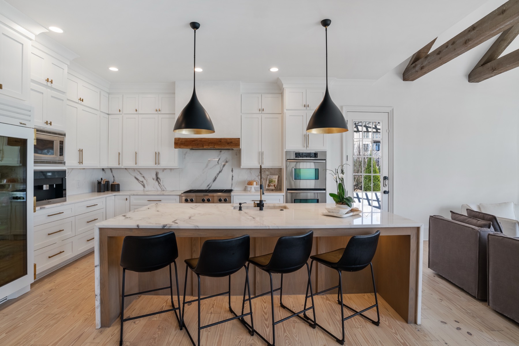 White kitchen with black pendant lighting and marble island seating