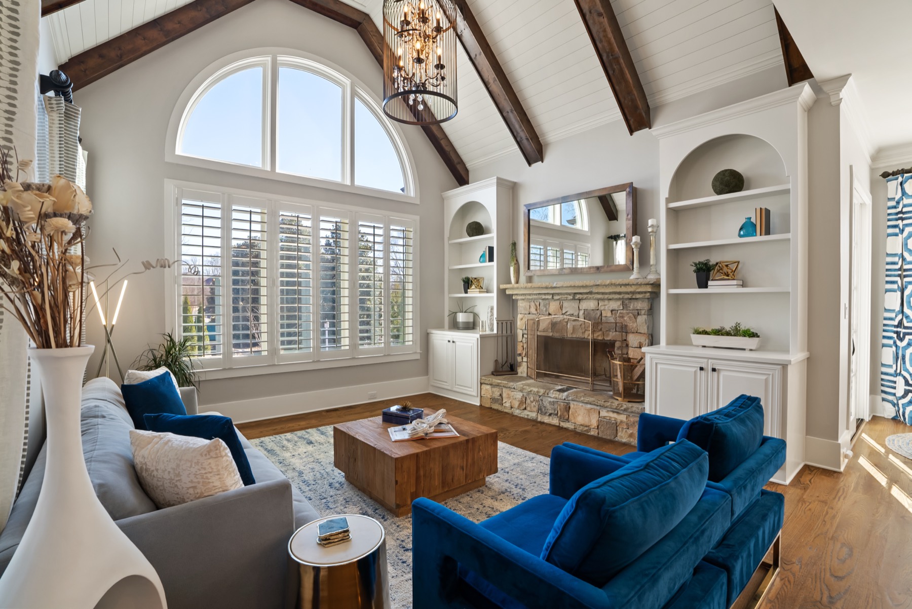 Living room with arched palladian window and stacked-stone fireplace