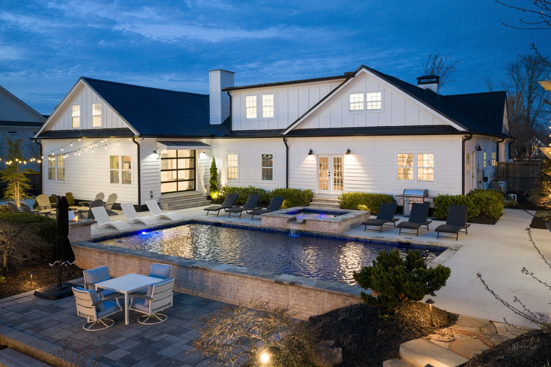 Farmhouse-style Atlanta home exterior at dusk with pool and spa