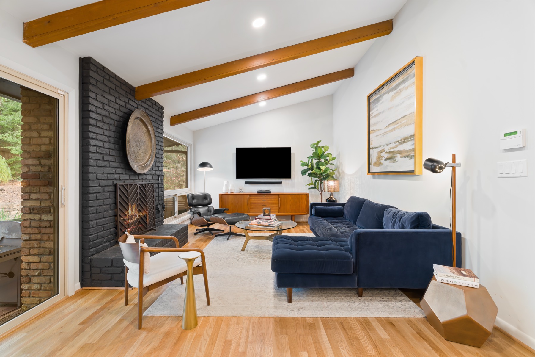 Mid-century living room with black brick fireplace and navy velvet sectional